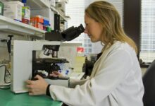 woman in white coat holding black dslr camera
