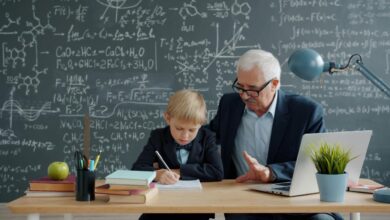 Elderly man teaching young boy math at desk.
